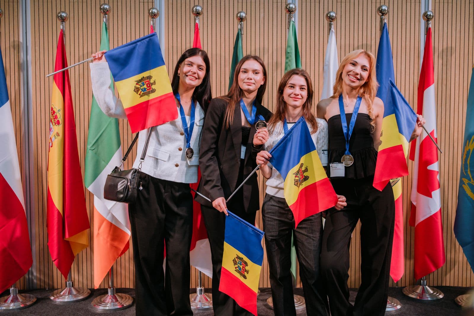 Membrele echipei zâmbesc și țin steaguri mici ale Moldovei
